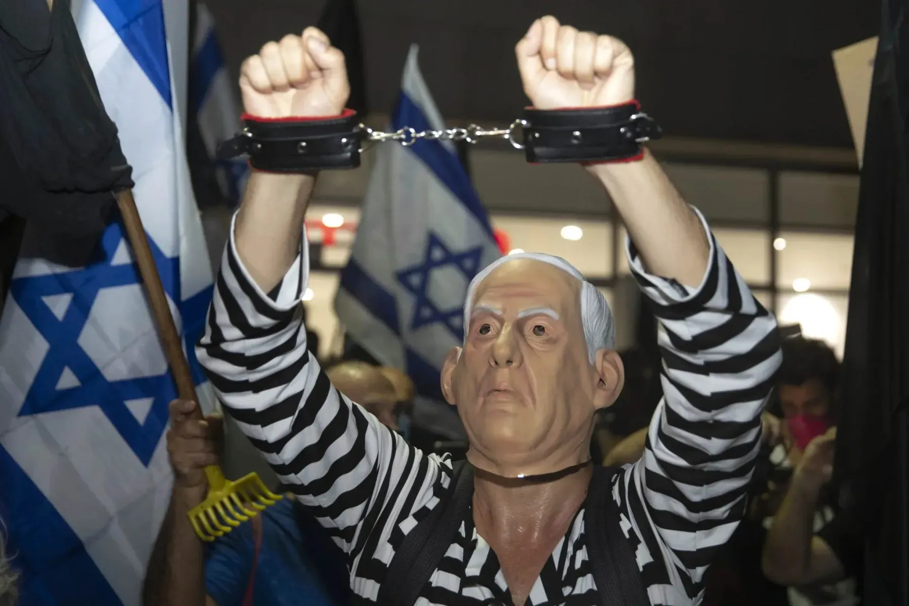 Protester in Israel wearing a mask of prime minister Benjamin Netanyahu, dressed as a prisoner.